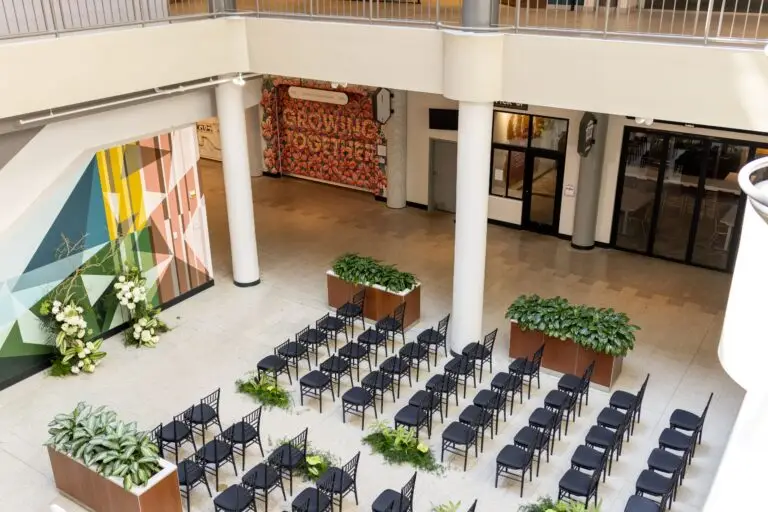 North Atrium at The Mercantile On Main set for a wedding ceremony, with rows of black chairs between planters and a colorful geometric mural, seen from the balcony above